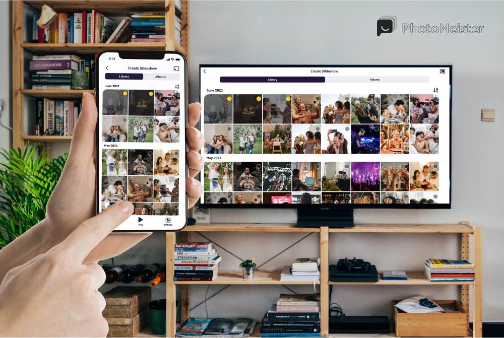 A hand holding an iPhone with PhotoMeister interface on the screen. A Smart TV with the PhotoMeister slideshow stream. the Tv is standing on a drawer