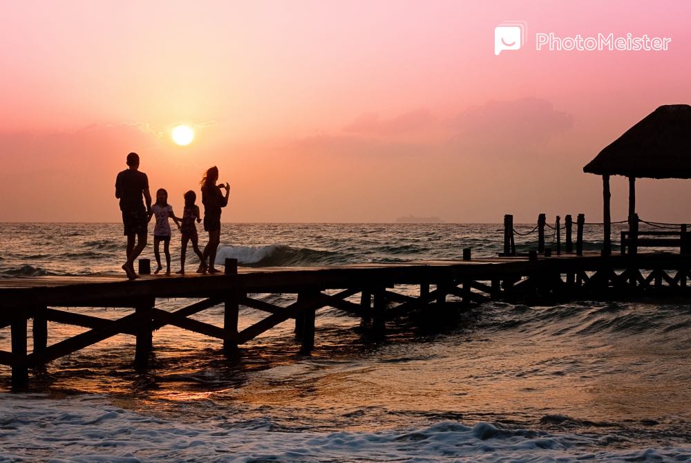 a family of four person watch the sunset at the beach