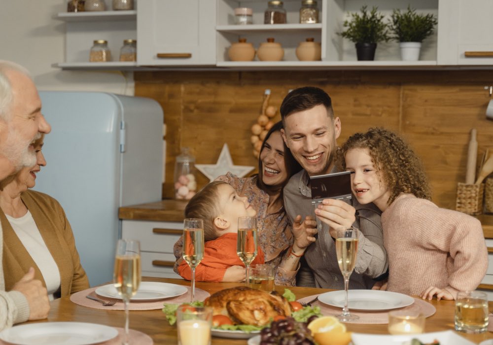 Mom, dad, son and daughter sit by the grandparents at a set table with glasses of champagne