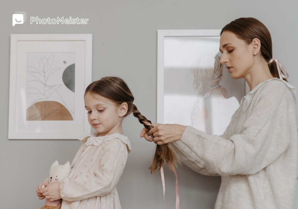 A young daughter stands with her back turned to her mom. The mom is braiding her daughter's hair